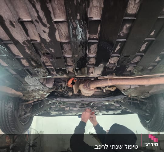 תחתית רכב במוסך עם מכונאי עובד